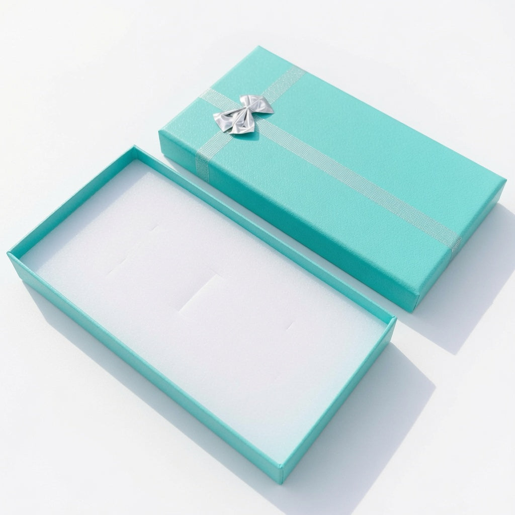 Open lake blue paper necklace box with silver ribbon bow and white insert