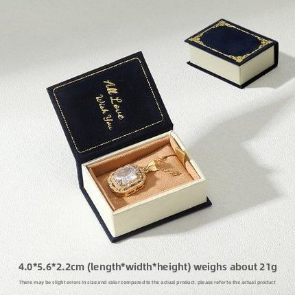 Navy book-shaped pendant box with tan insert and matching closed box on white