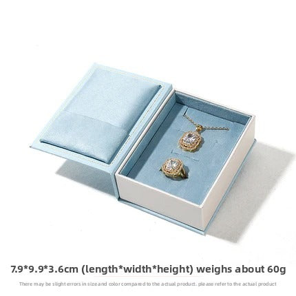 Open light blue book-shaped jewelry set box showing lid cushion and empty insert on white