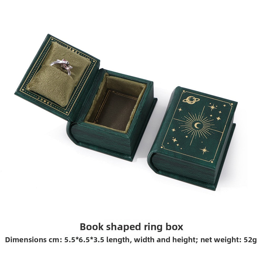 Green book-shaped ring box with olive velvet ring slot, shown open and closed