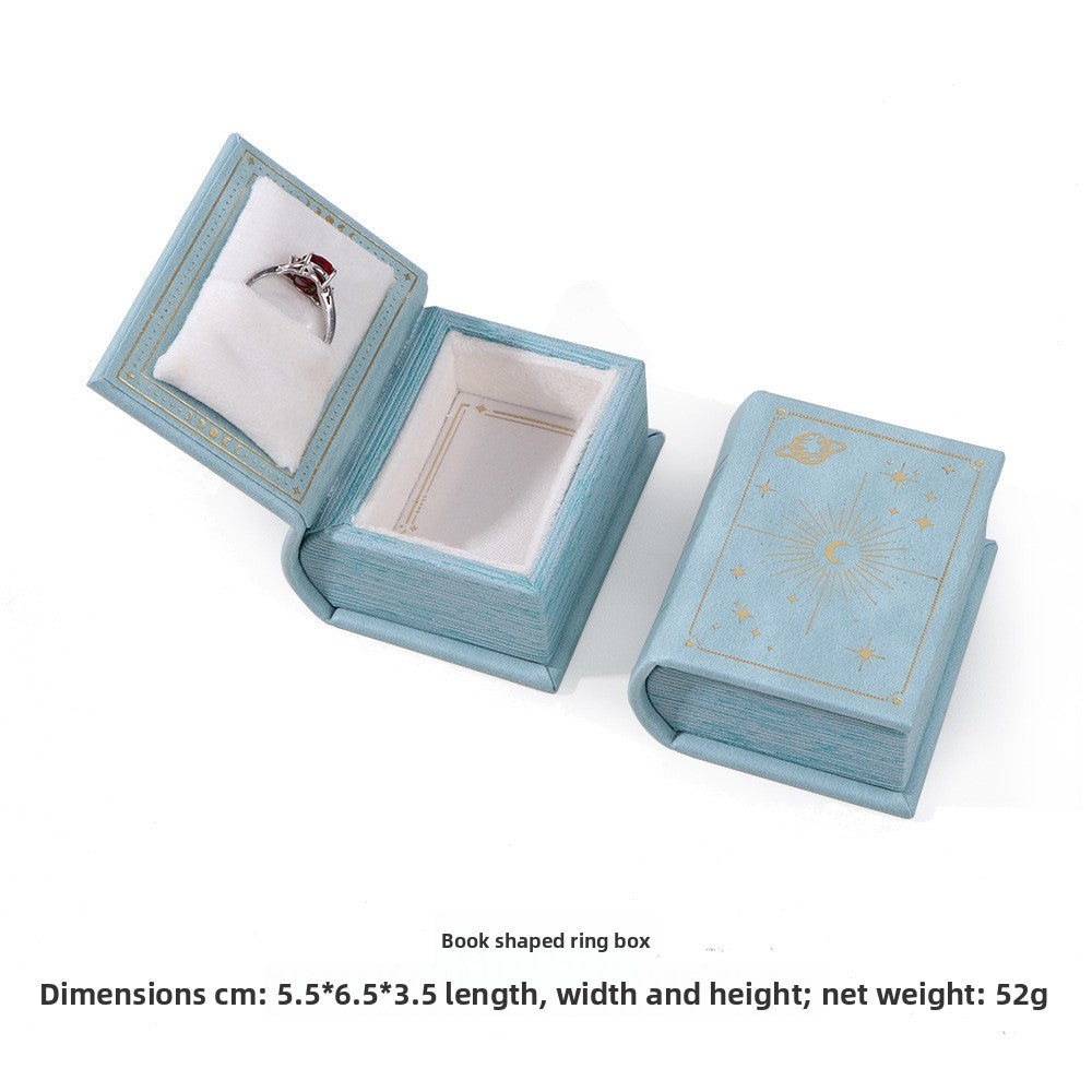 Light blue book-shaped ring box with white velvet ring slot, shown open and closed